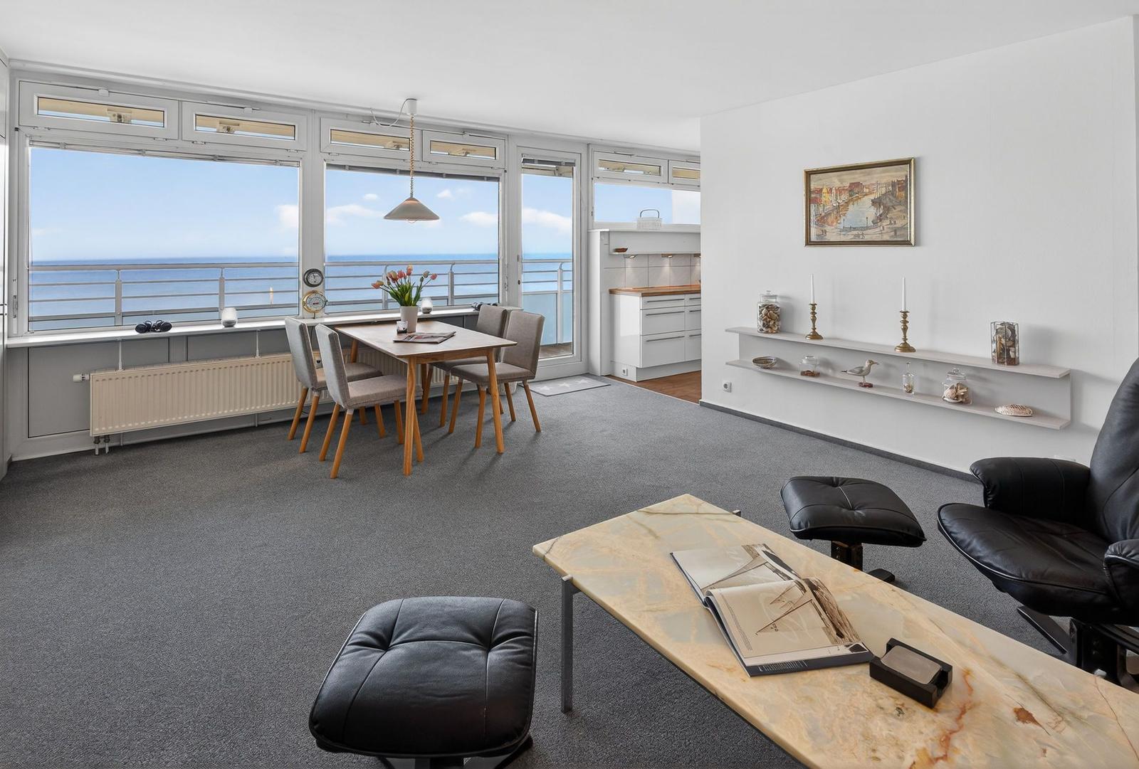 Living room with dining area and sea view. Black leather chairs and marble table.