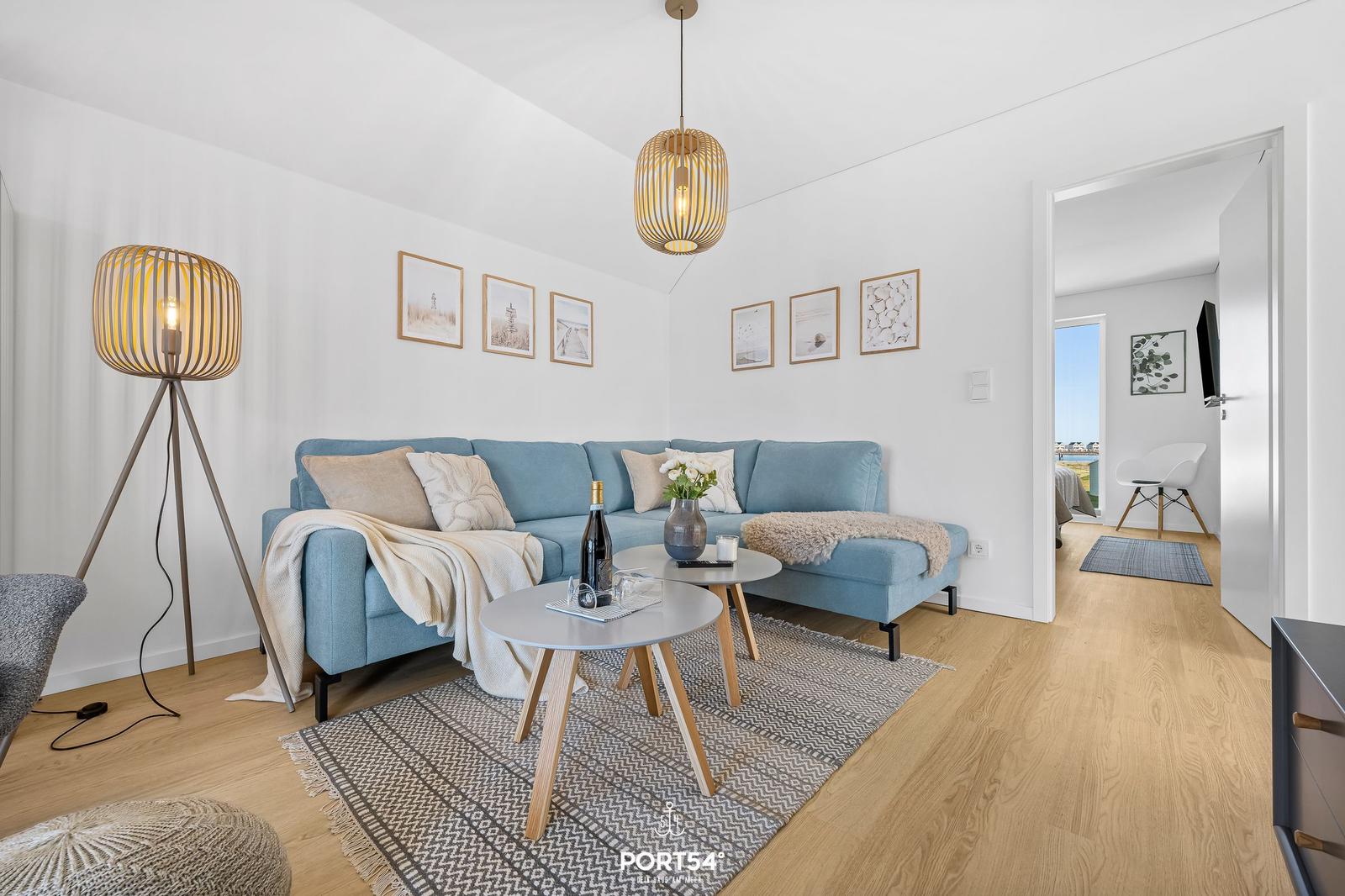 Ein Wohnzimmer mit blauem Sofa, zwei runden Tischen und einem Holzboden.