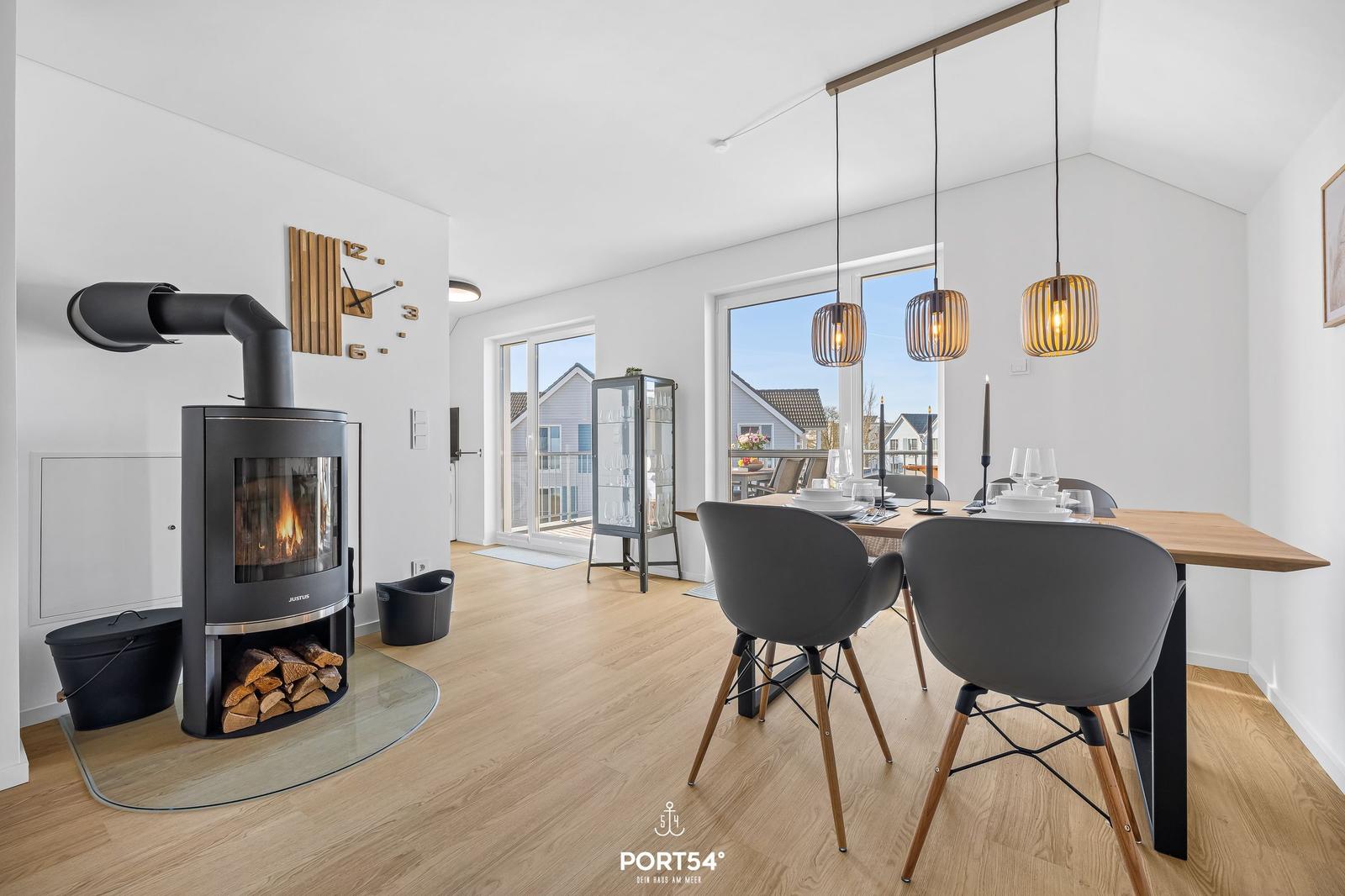 Essbereich mit Tisch, Stühlen und Hängelampen. Kamin und Holzfußboden sind sichtbar.