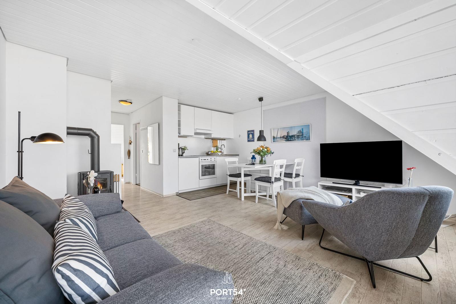 Wohnbereich mit Sofa, Fernseher und Essbereich unter Dachschräge.