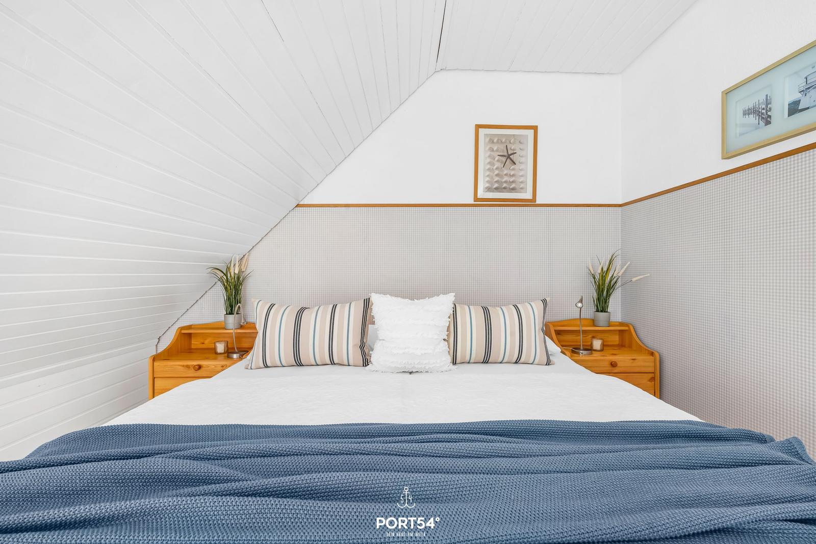 Schlafzimmer mit Dachschrägen, Holz-Nachttischen und gemütlicher Bettwäsche.