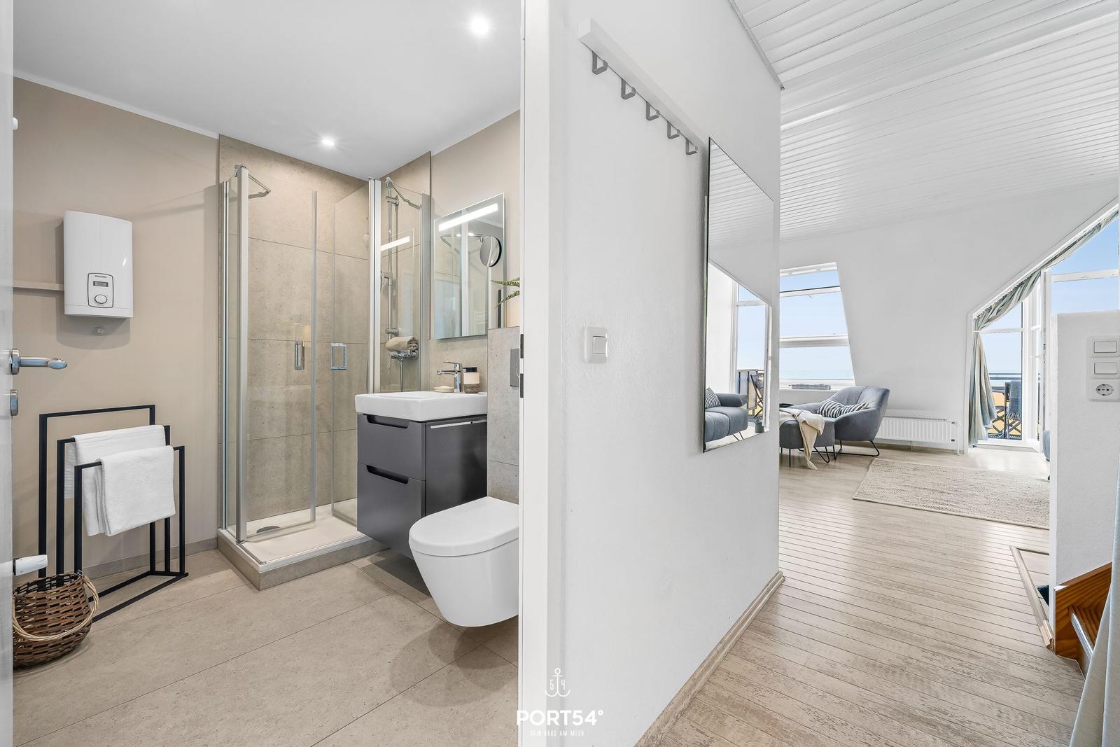 Badezimmer mit Dusche und WC. Durchgang in Wohnbereich mit Blick aufs Meer.