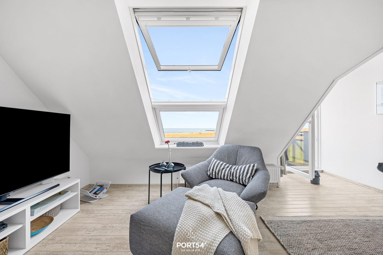 Dachgeschosswohnung mit Sitzgelegenheit und Dachfenster zum Meer