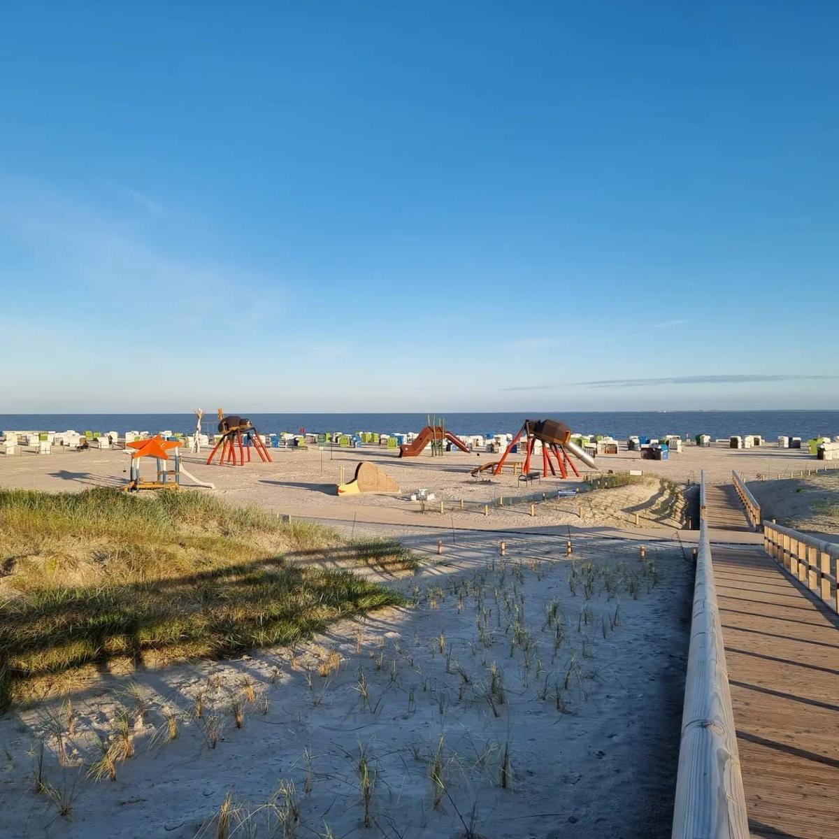 Holzweg führt zum Strand mit Spielplatz und Strandkörben.