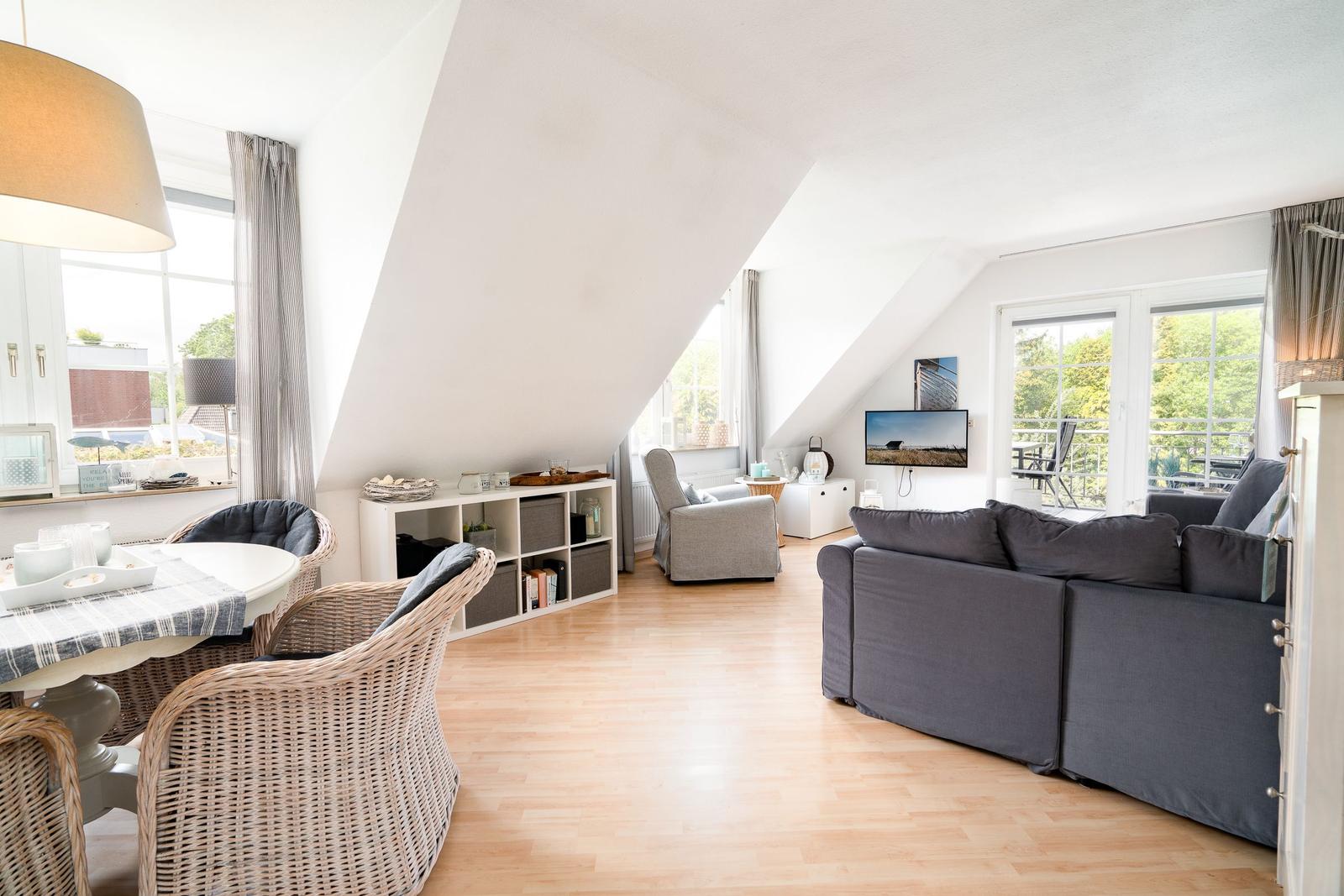 Wohnbereich mit Sofa, Esstisch und TV unter Dachschrägen.