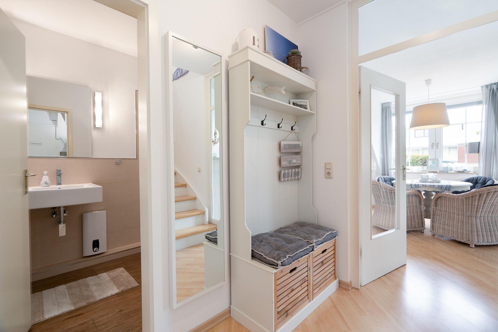 Eingangsbereich mit Garderobe, Spiegel und Blick in Bad und Wohnzimmer.