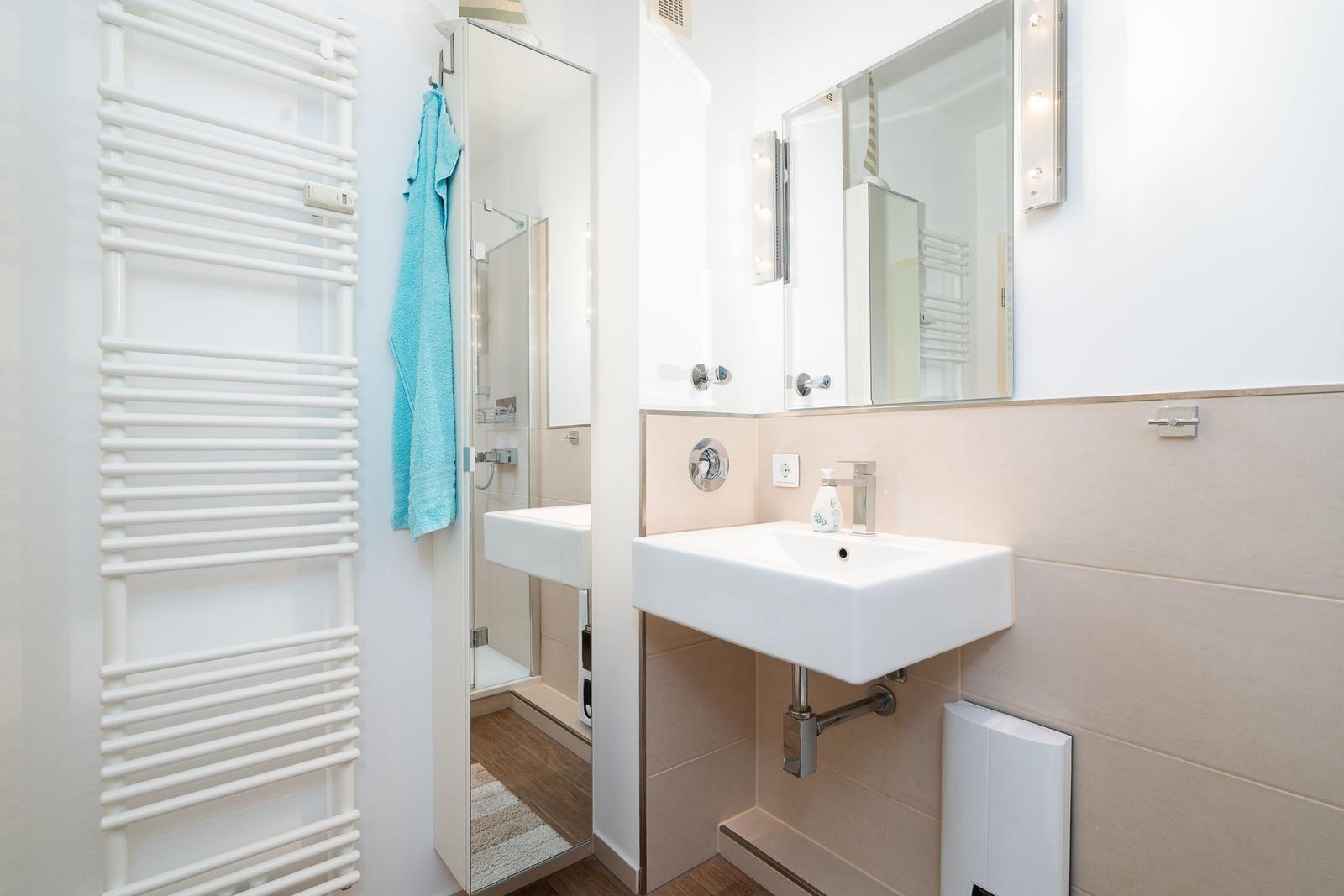 Badezimmer mit Waschbecken, Spiegel und Dusche