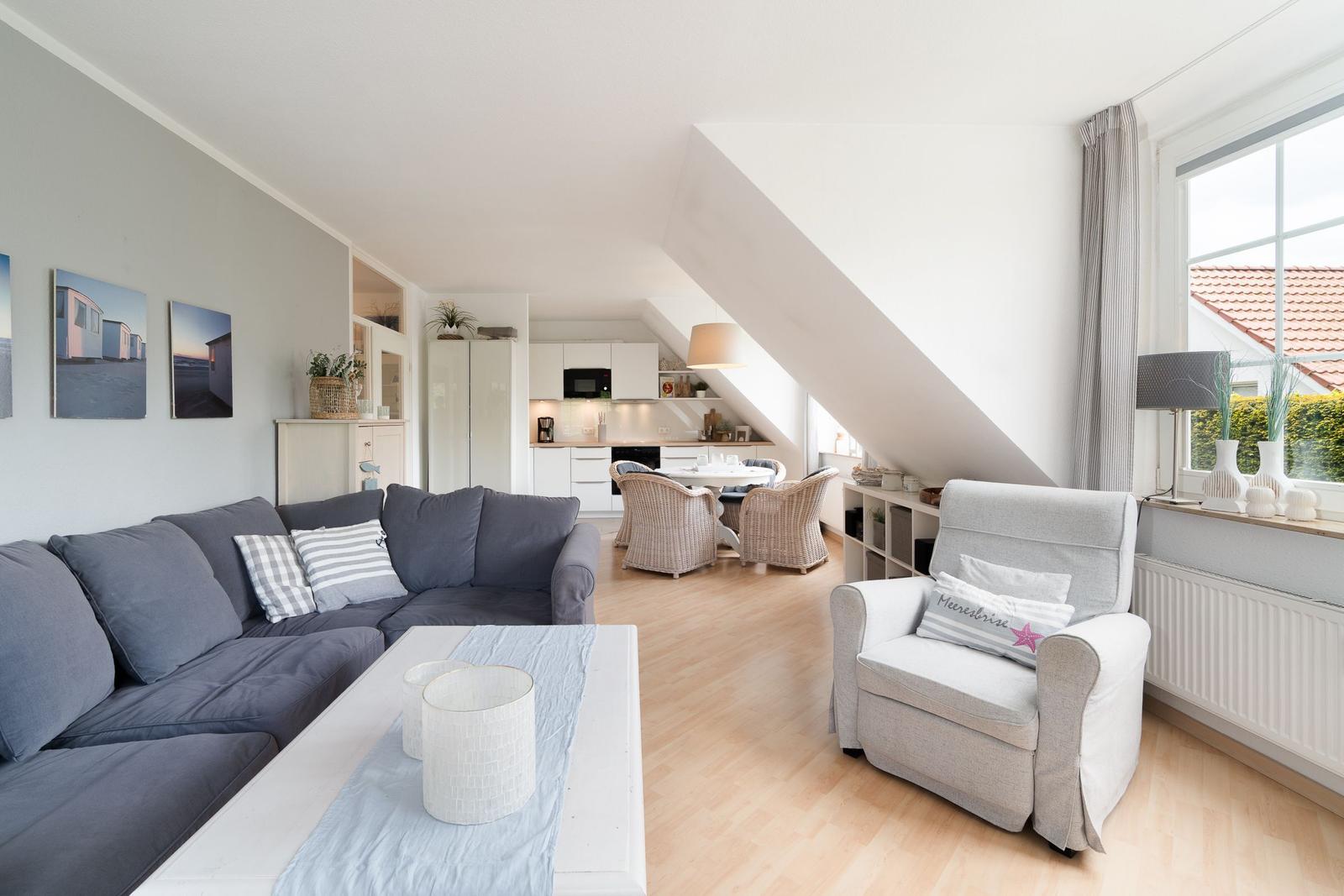Wohnzimmer mit Sofa, Sessel und Essbereich unter Dachschräge.