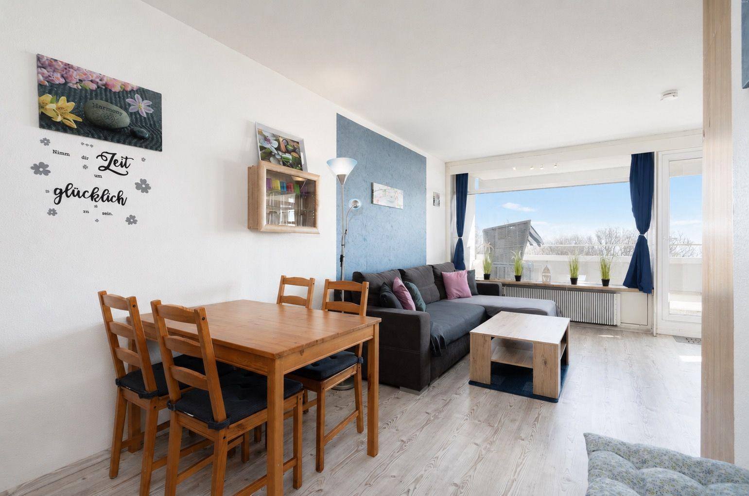 Wohn- und Essbereich mit Sofa, Tisch und Stühlen. Balkon mit Blick. Wanddekoration.