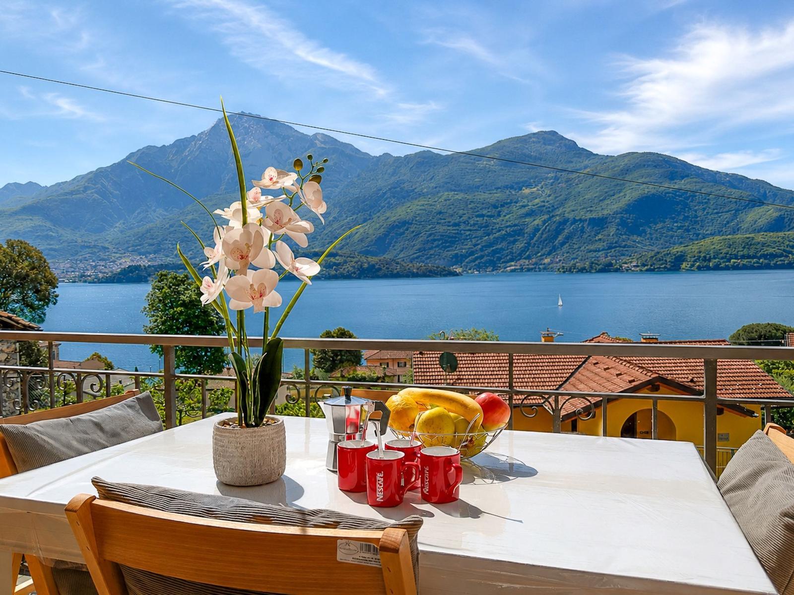 Terrace with table, flowers and fruit view of lake and mountains