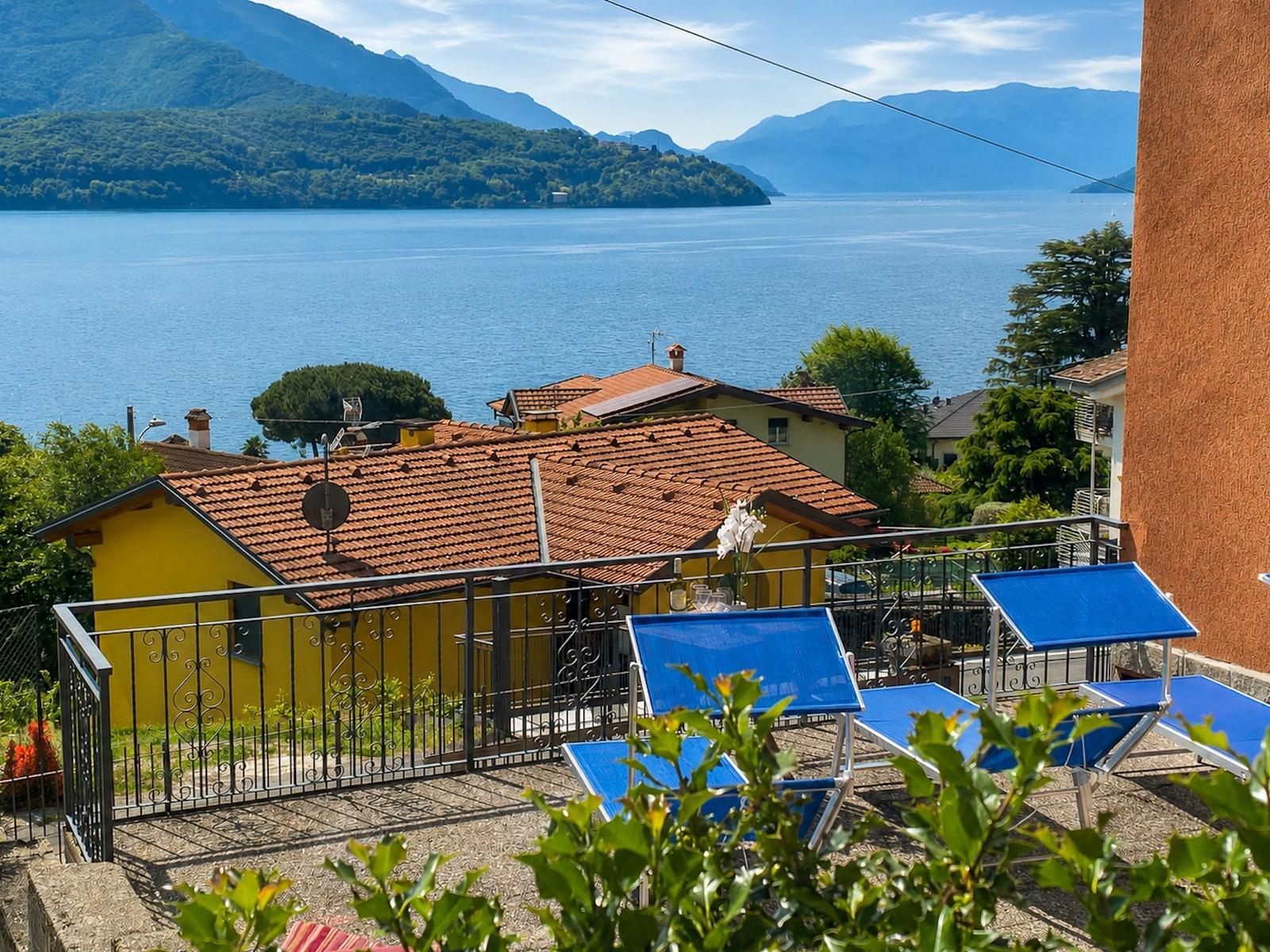 Terrace with blue sun loungers and view of lake and mountains.