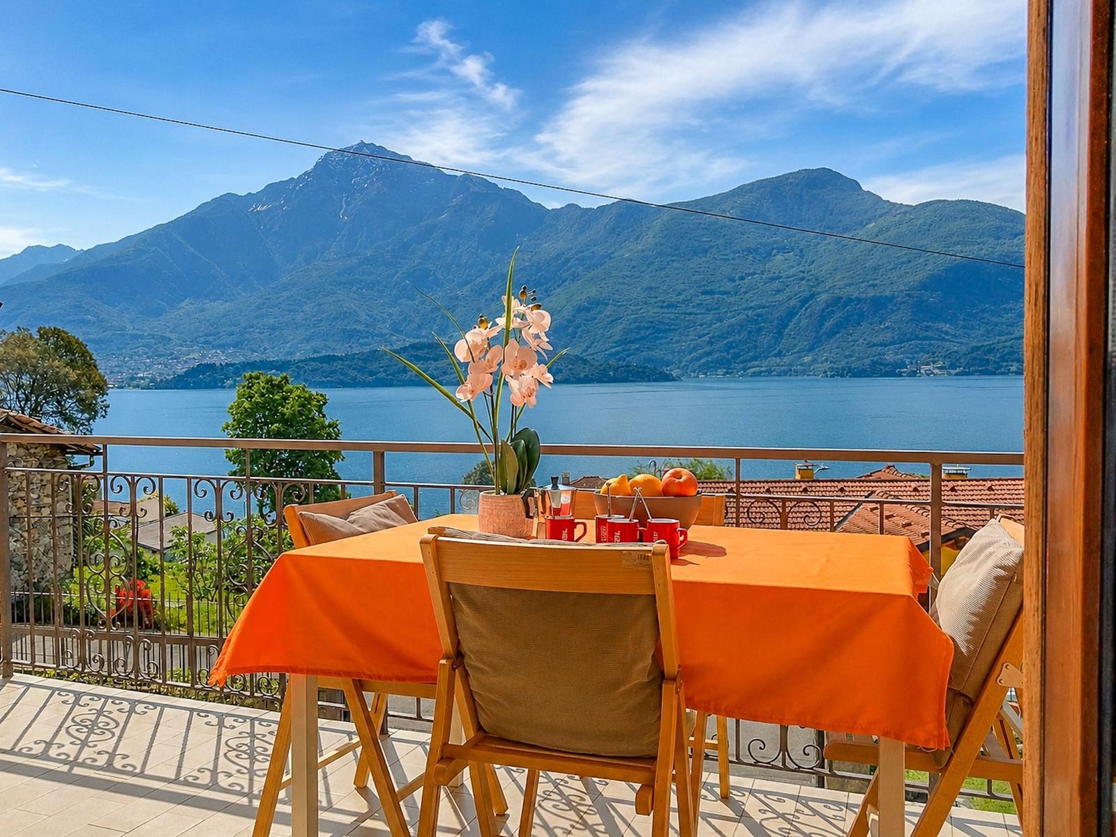 Terrace with table and chairs, view of lake and mountains.