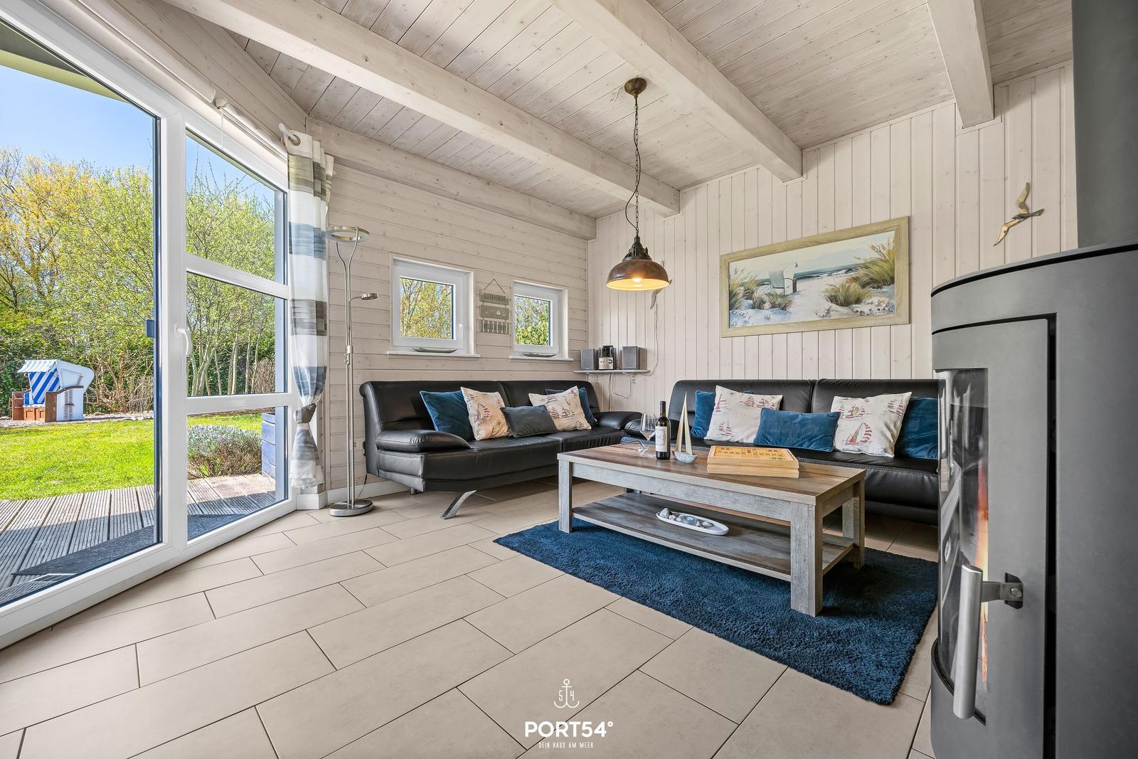 Wohnzimmer mit Sofa, Kamin und Blick auf Garten