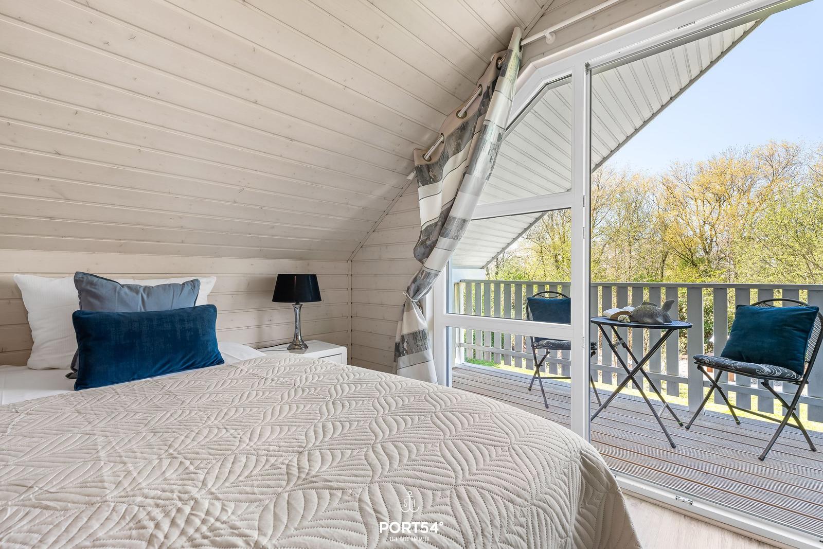 Schlafzimmer mit Balkon und Bett. Blick auf Bäume.