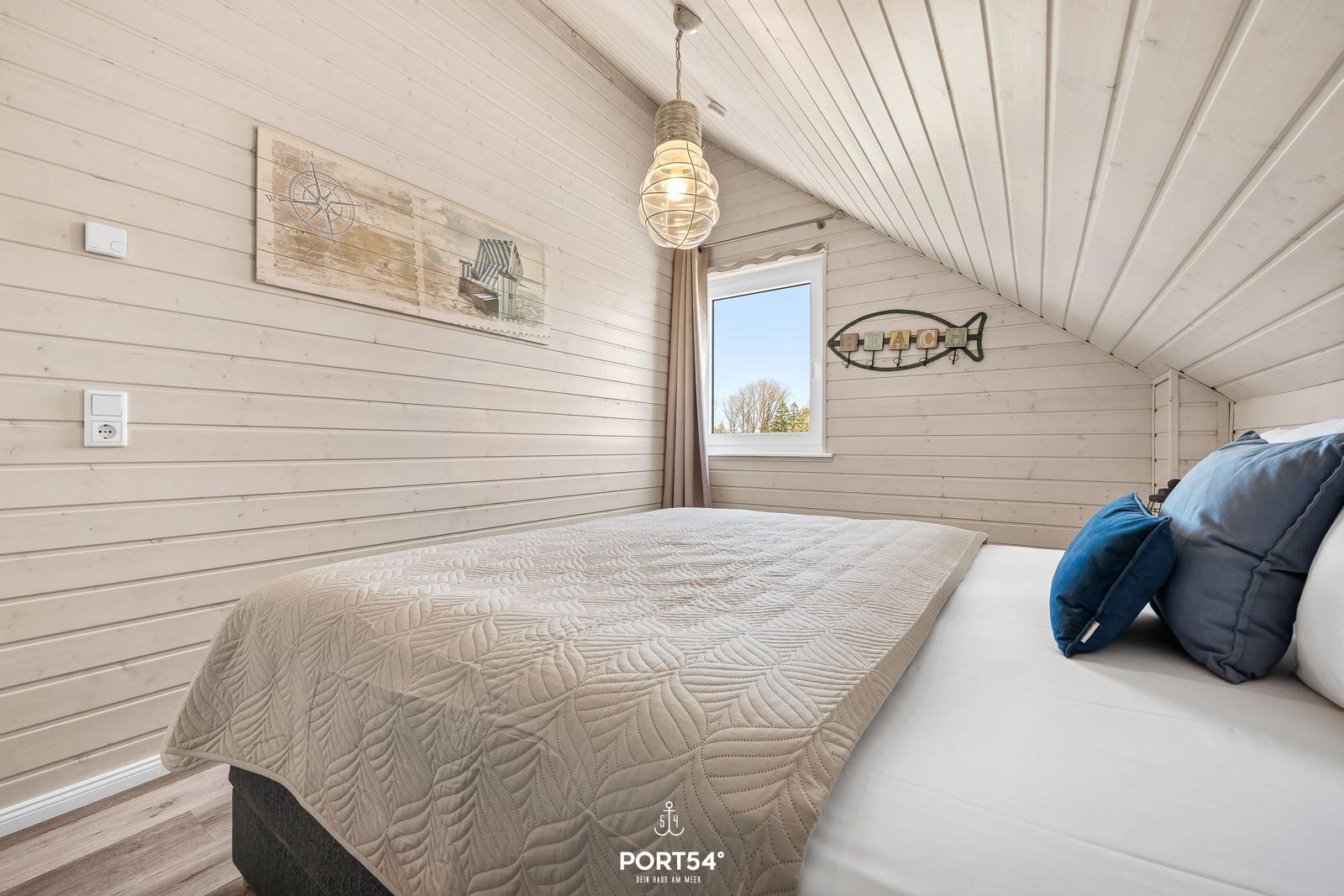Schlafzimmer mit Bett, Wandbild und Fenster. Holzwände und Decke.