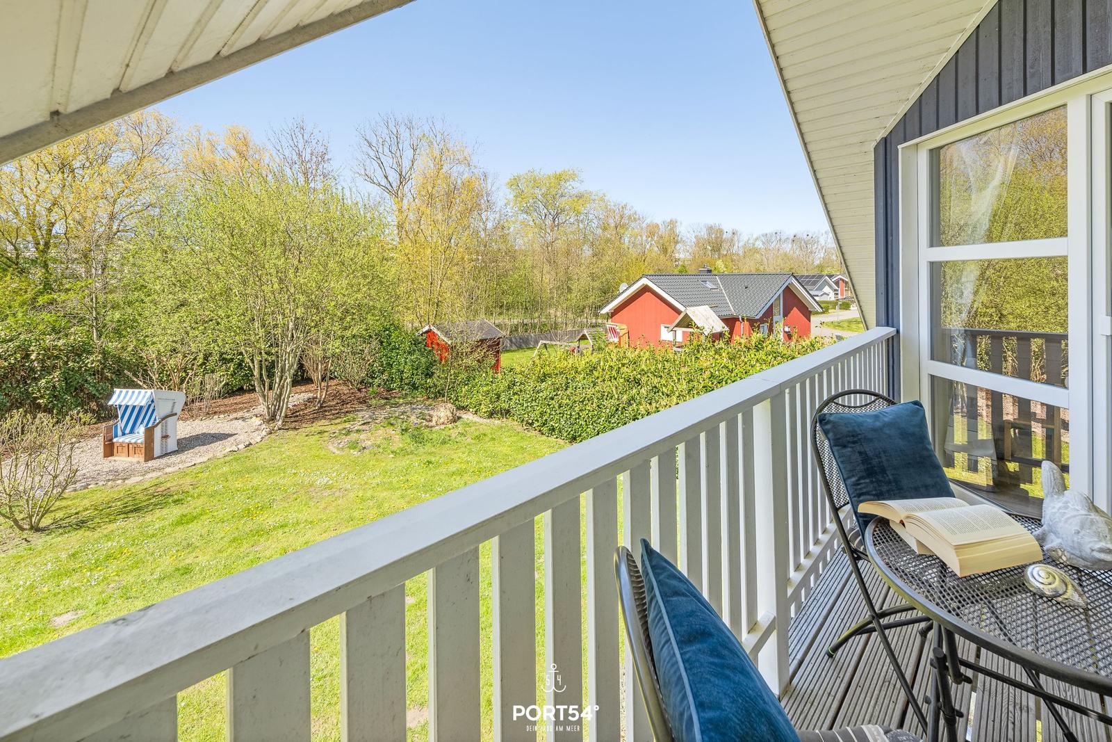 Terrasse mit Sitzgelegenheit und Blick auf Grünfläche und rote Häuser.