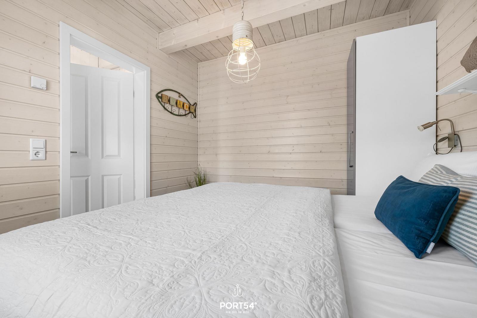 Schlafzimmer mit Holzwand, Bett und Lampen