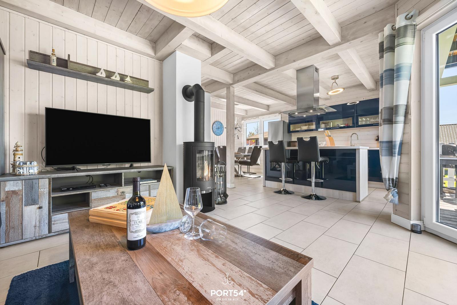 Wohnbereich mit Kamin, TV und Küchenzeile im Hintergrund.