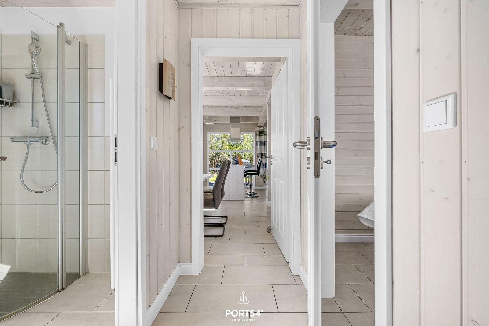 Flur mit Dusche links und Blick in Küche und Schlafzimmer rechts.