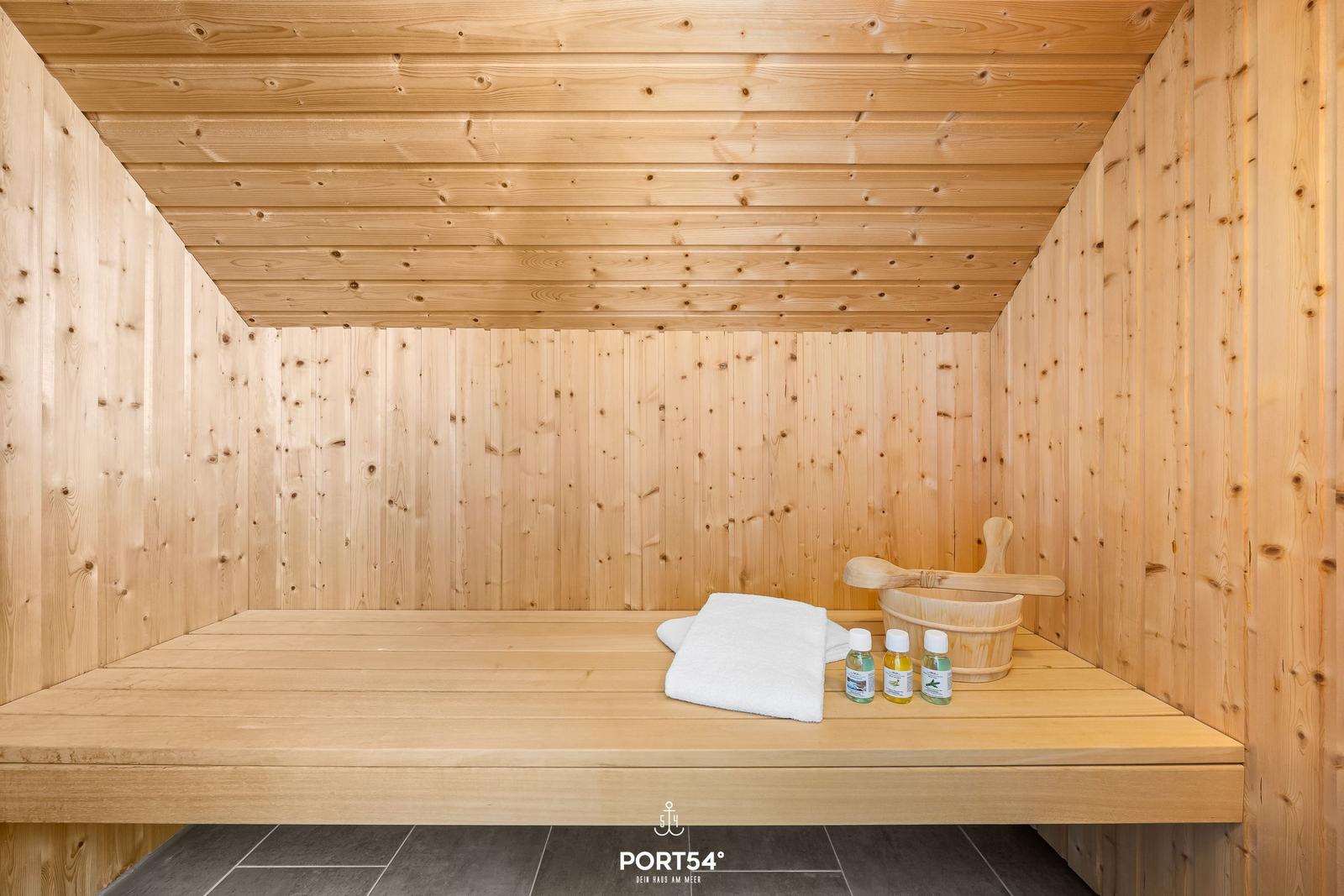 Holzsauna mit Bank, Handtuch und Saunabehälter.