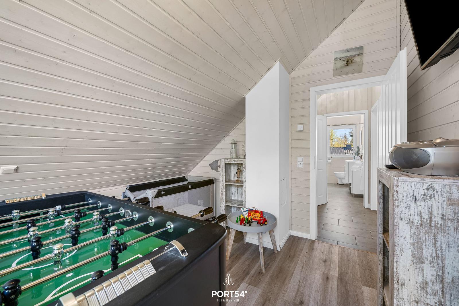 Fussballtisch im Dachzimmer mit Blick in das Badezimmer.