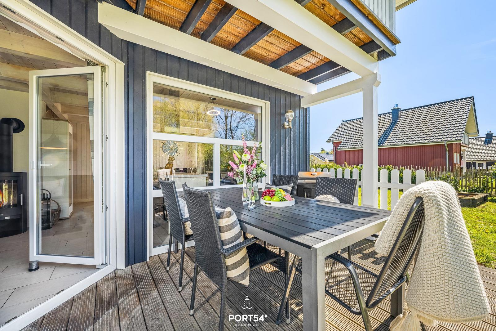 Terrasse mit Tisch und Stühlen, Blick auf Garten und Nachbarhaus.