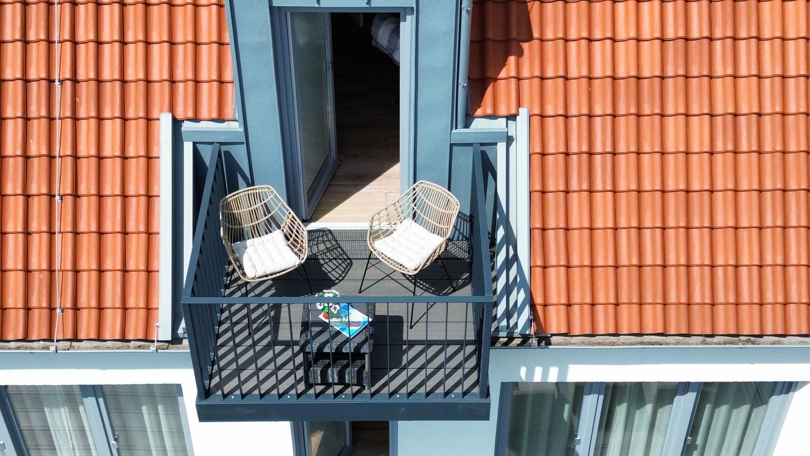 Terrasse mit zwei Stühlen und Tisch zwischen roten Ziegeldächern