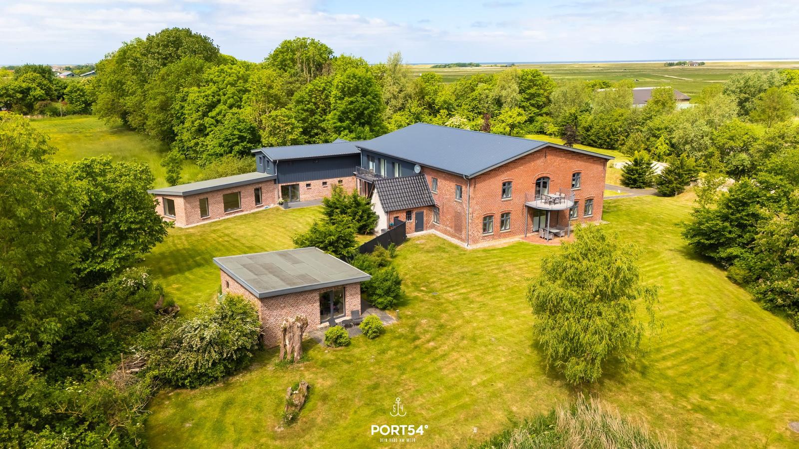 Roter Backsteinbau mit moderner Veranda und großem Garten. Blick auf die Landschaft.