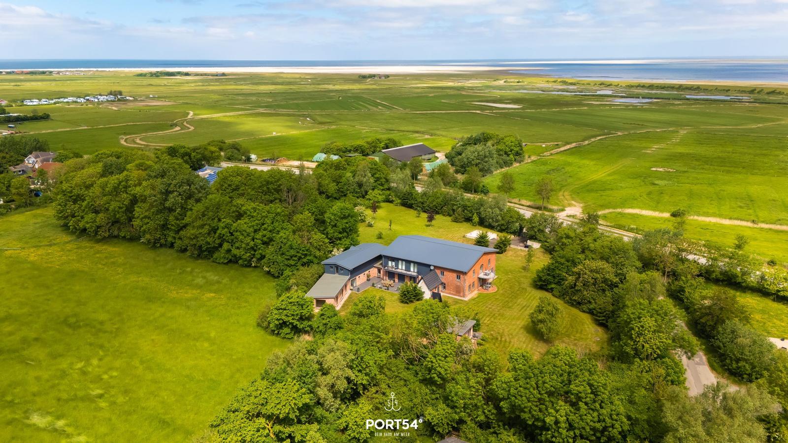 Haus mit Garten, umgeben von Wiesen und Wald, Blick auf das Meer.