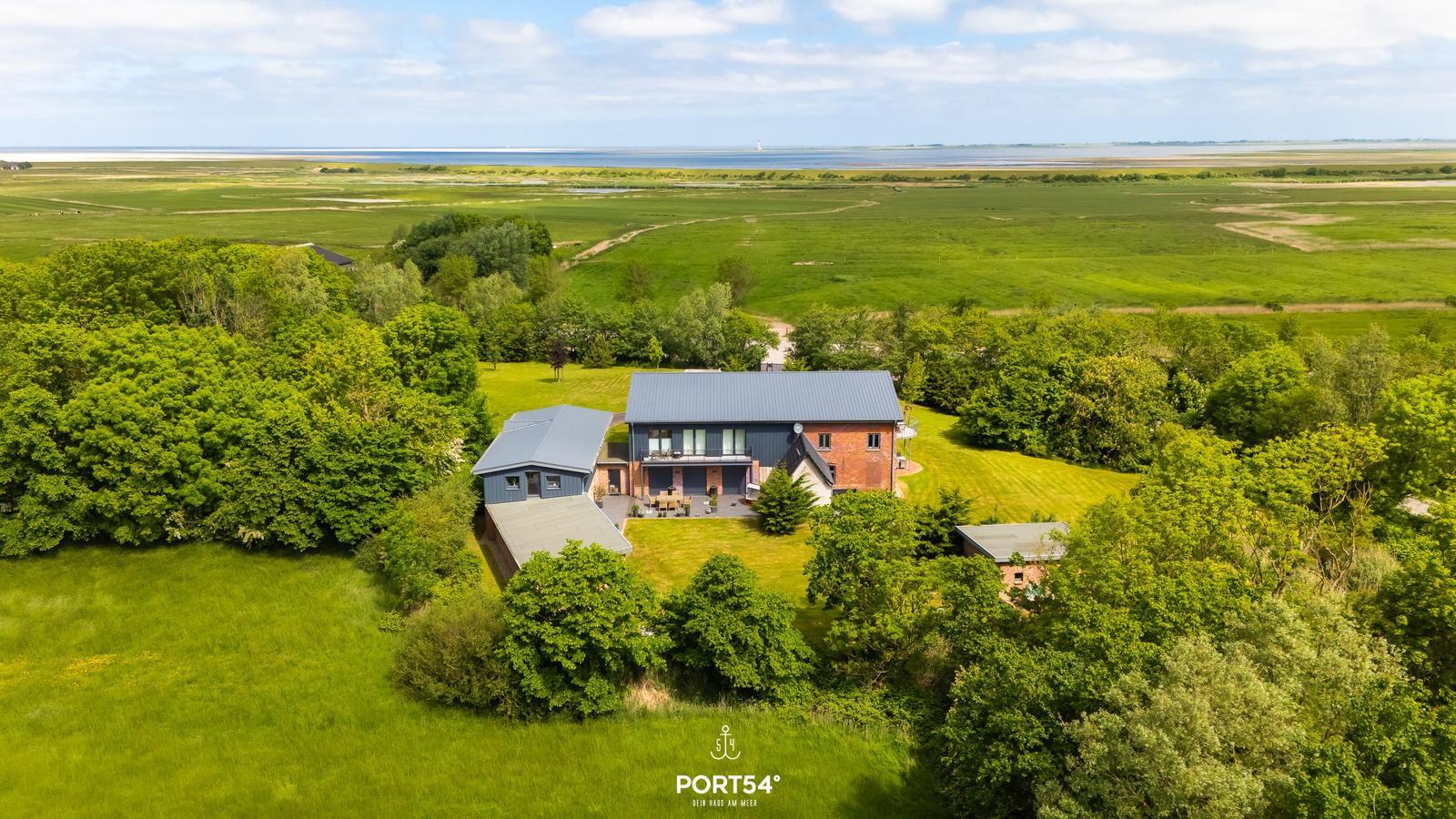 Modernes Haus mit Terrasse, umgeben von Grünland und Wald, Blick auf die Nordsee.