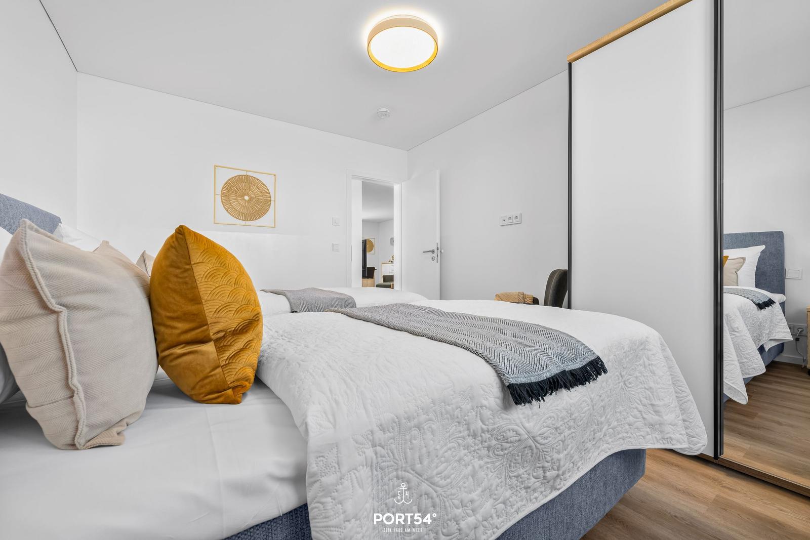 Schlafzimmer mit Bett, Kissen und Spiegeltüren.