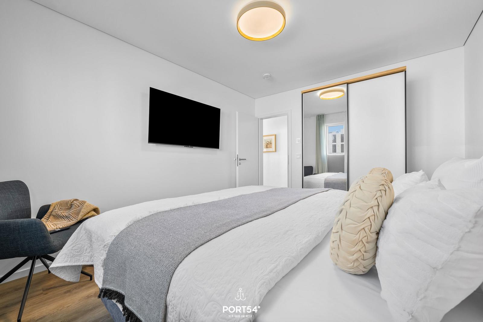 Schlafzimmer mit Bett, Fernseher und Kleiderschrank