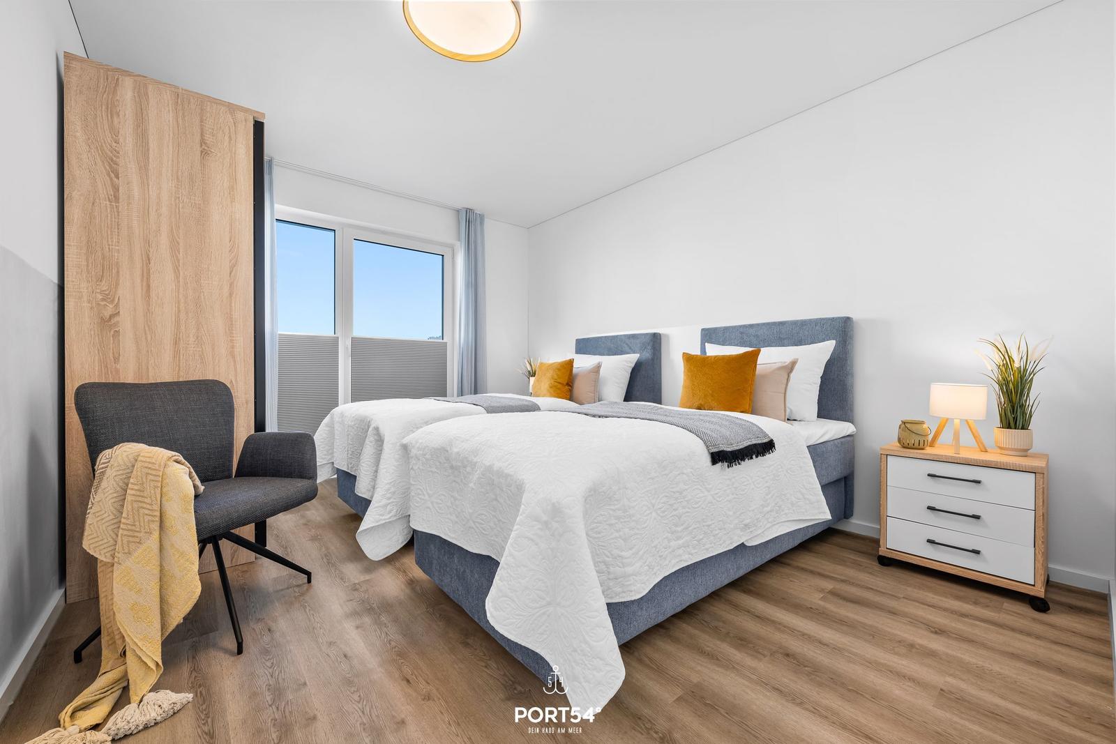 Schlafzimmer mit Doppelbett, Nachttisch, Sessel und Fenster mit Blick.