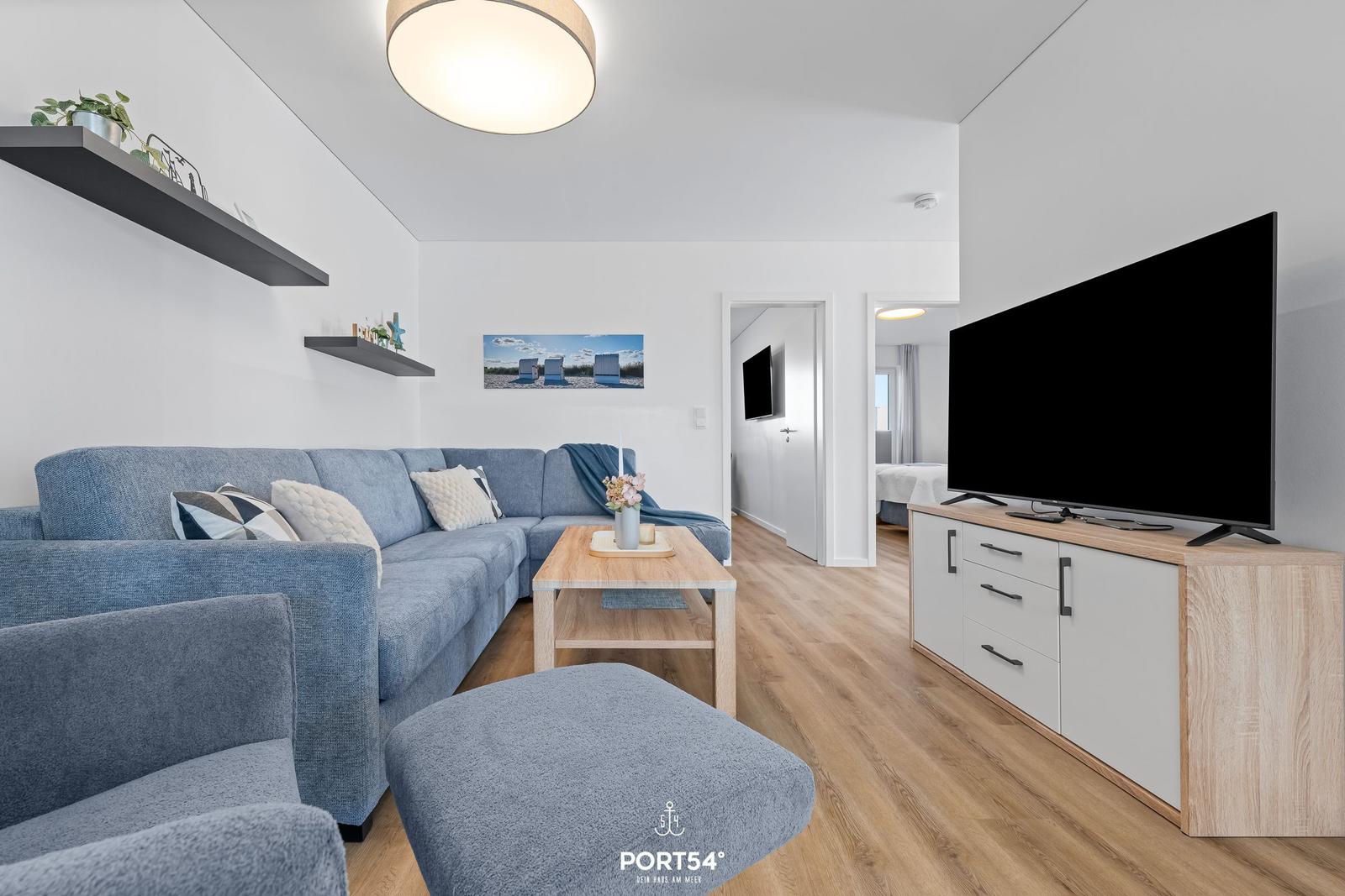 Wohnzimmer mit Sofa, TV und Holzboden.