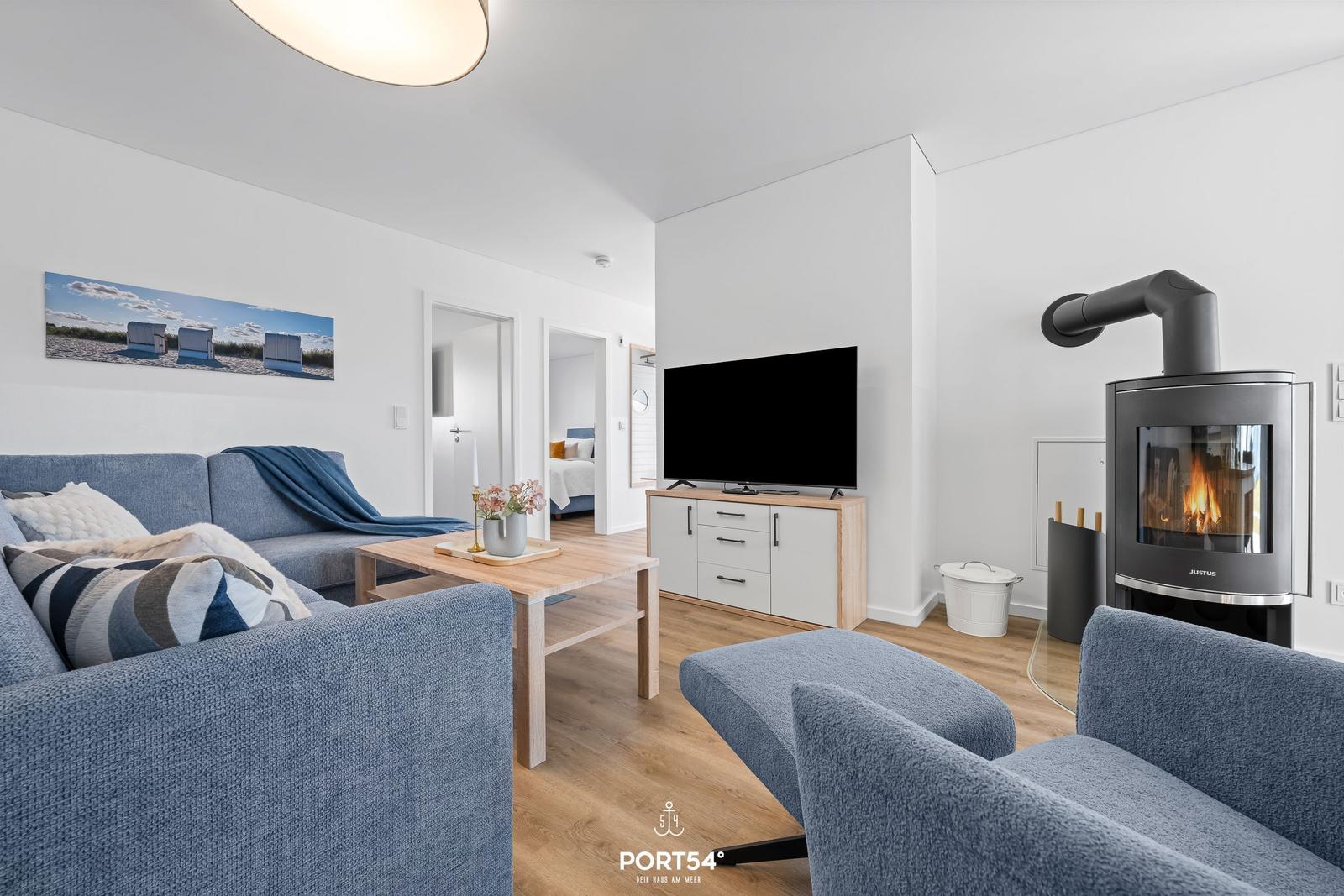 Wohnzimmer mit Sofa, Kamin und Fernseher. Durchgang zu Schlafzimmer.