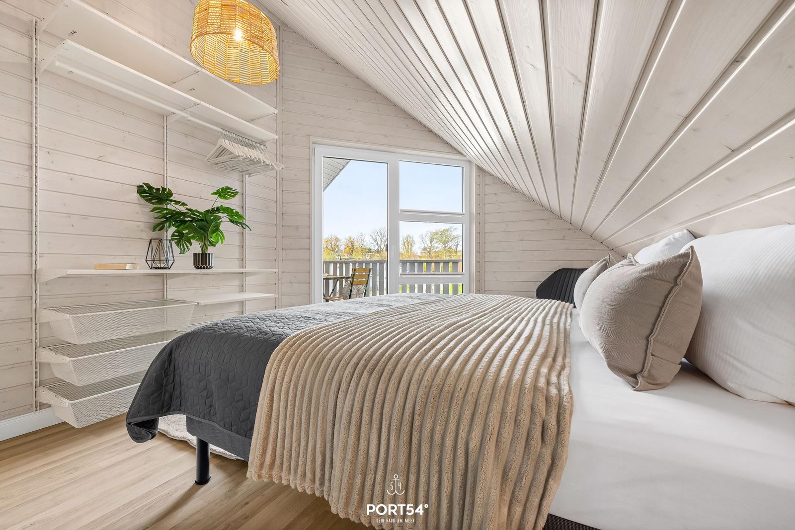 Schlafzimmer mit Bett, Kleiderschrank und Balkonblick