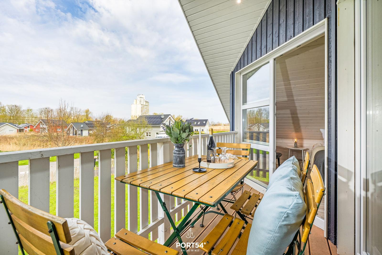 Terrasse mit Tisch, Stühlen und Blick auf Wohngebiet und Hochhaus.