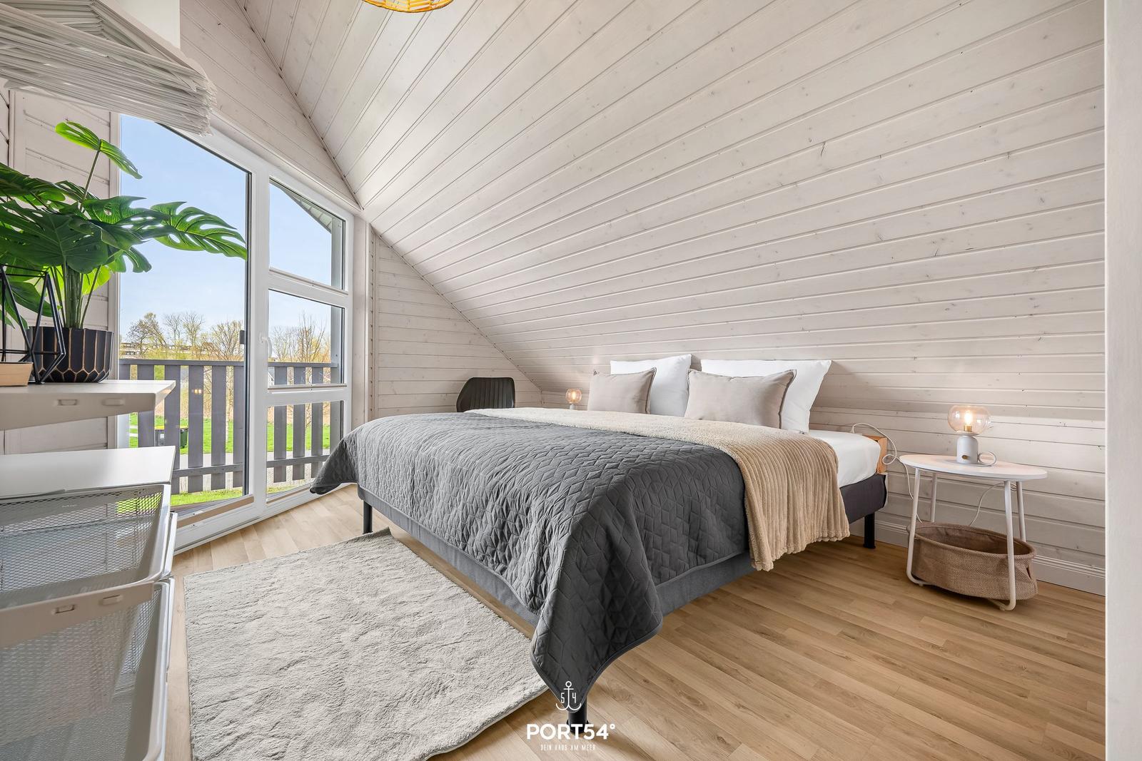 Schlafzimmer mit Bett, Nachttisch und Fenster zur Terrasse.