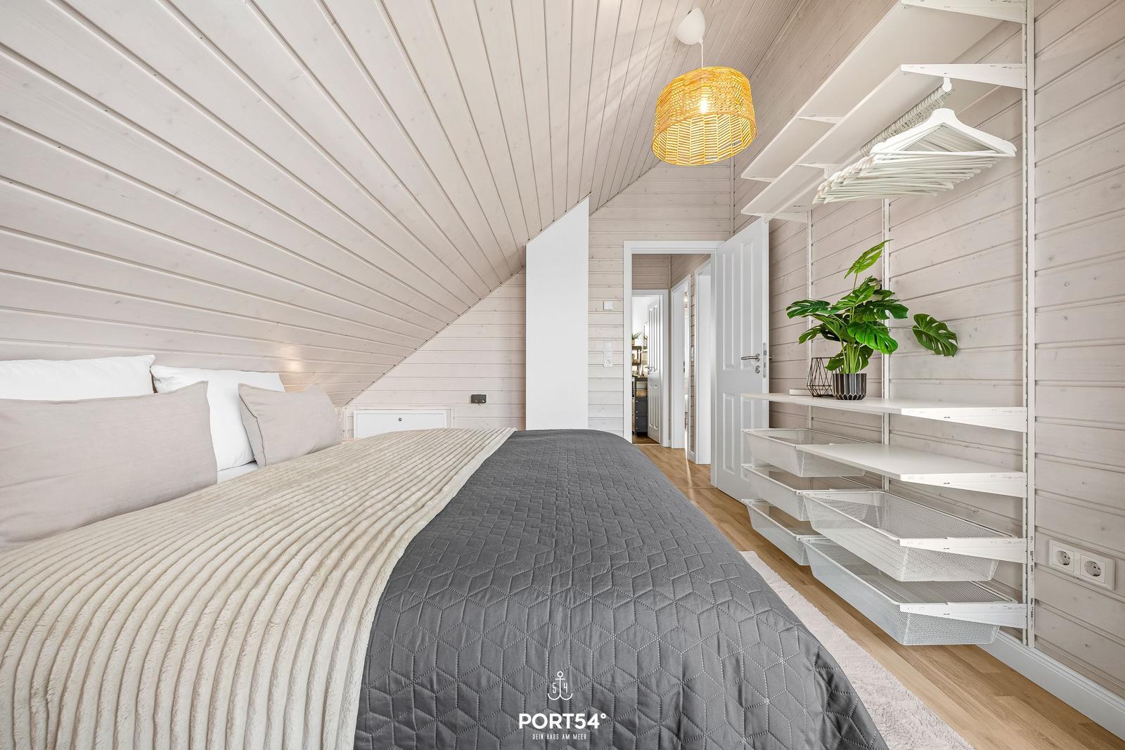 Schlafzimmer mit Bett, Kleiderschrank und Decke. Holzwände und Decke. Lampe und Pflanze.