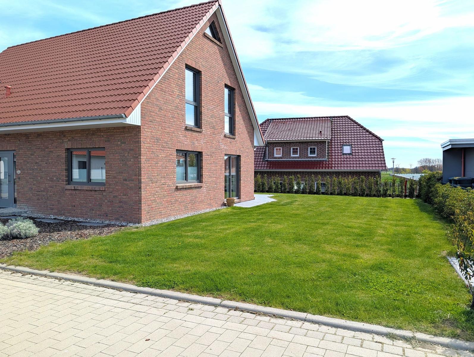 Zweistöckiges Haus mit rotem Dach und grünem Rasen vorne.