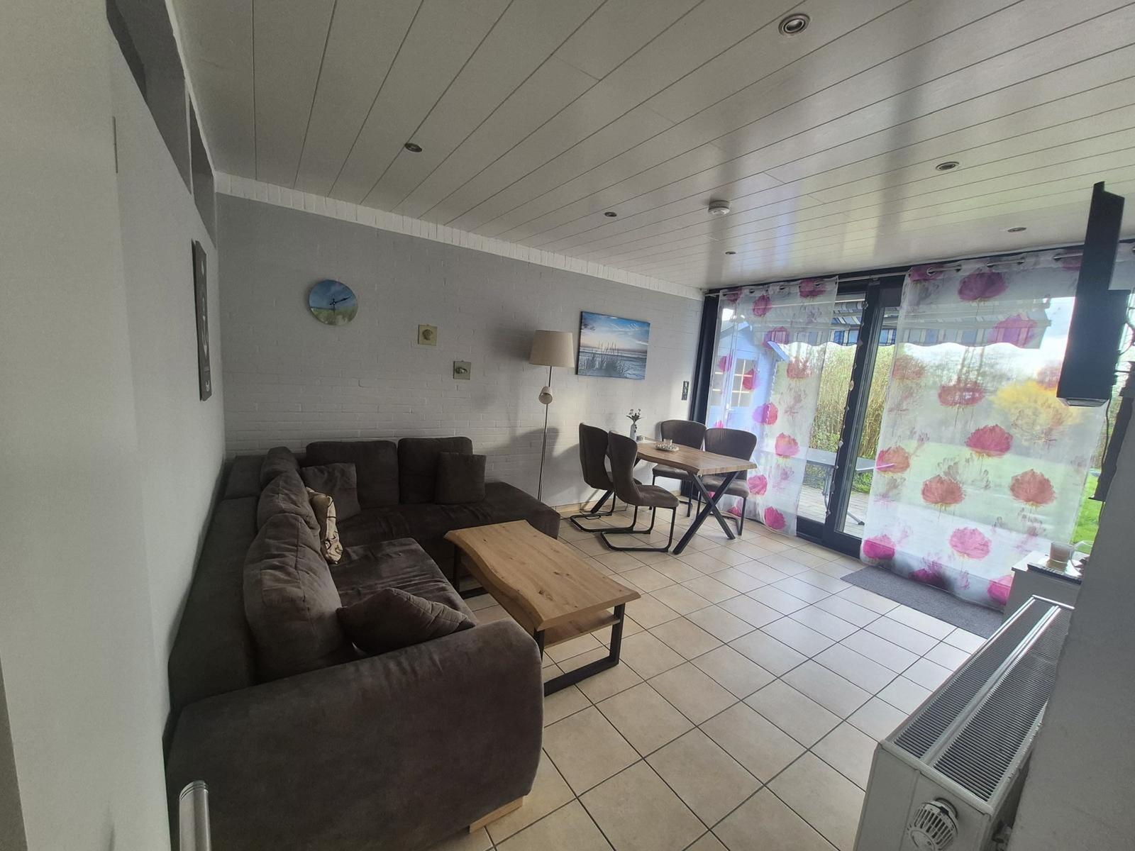 Living and dining area with sofa, table, and view of the terrace.
