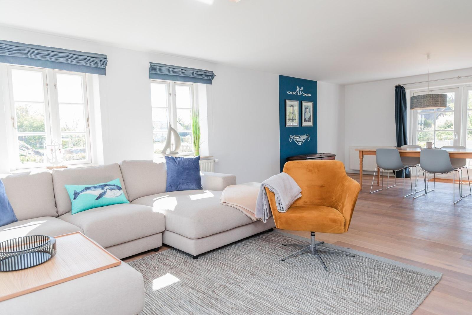 Wohnzimmer mit Sofa, Sessel und Essbereich. Blaue Wand und Holzboden.