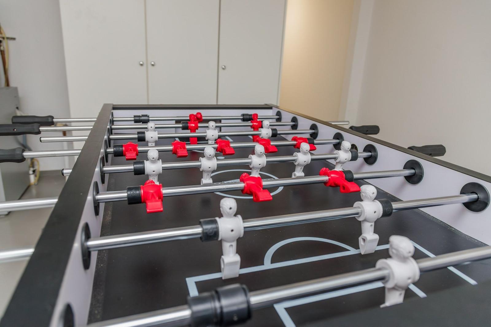 Fussballtisch mit roten und weißen Figuren und Metallstangen.
