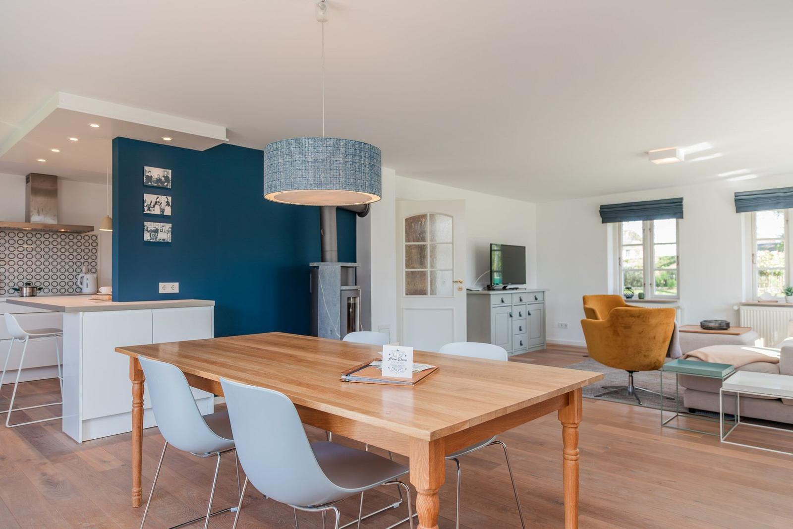 Essbereich mit Holztisch und Stühlen. Küche und Wohnzimmer im Hintergrund.