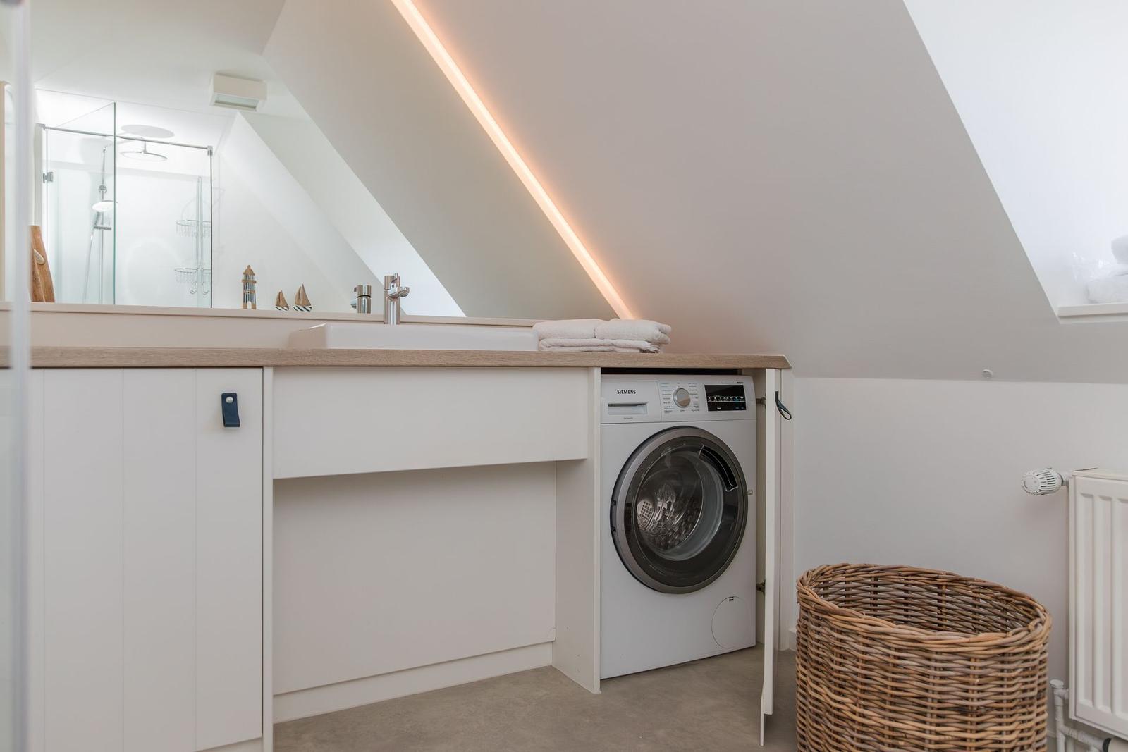 Waschmaschine unter Schrank, Spiegel und Duschbereich im Dachgeschoss