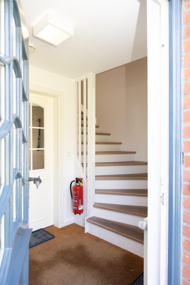 Eingangsbereich mit Treppe, Feuerlöscher und Tür.