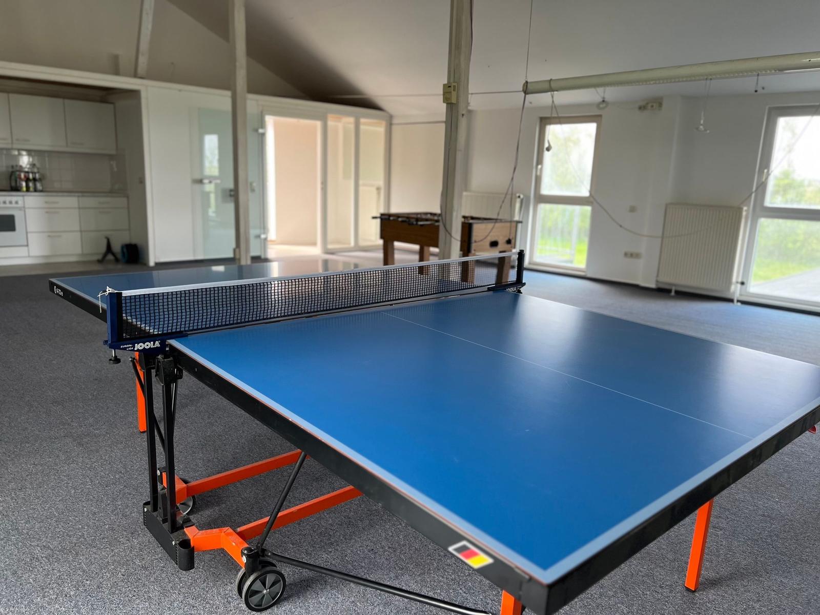 Tischtennis-Tisch in einer geräumigen Halle mit Blick auf Küche und Fenster.