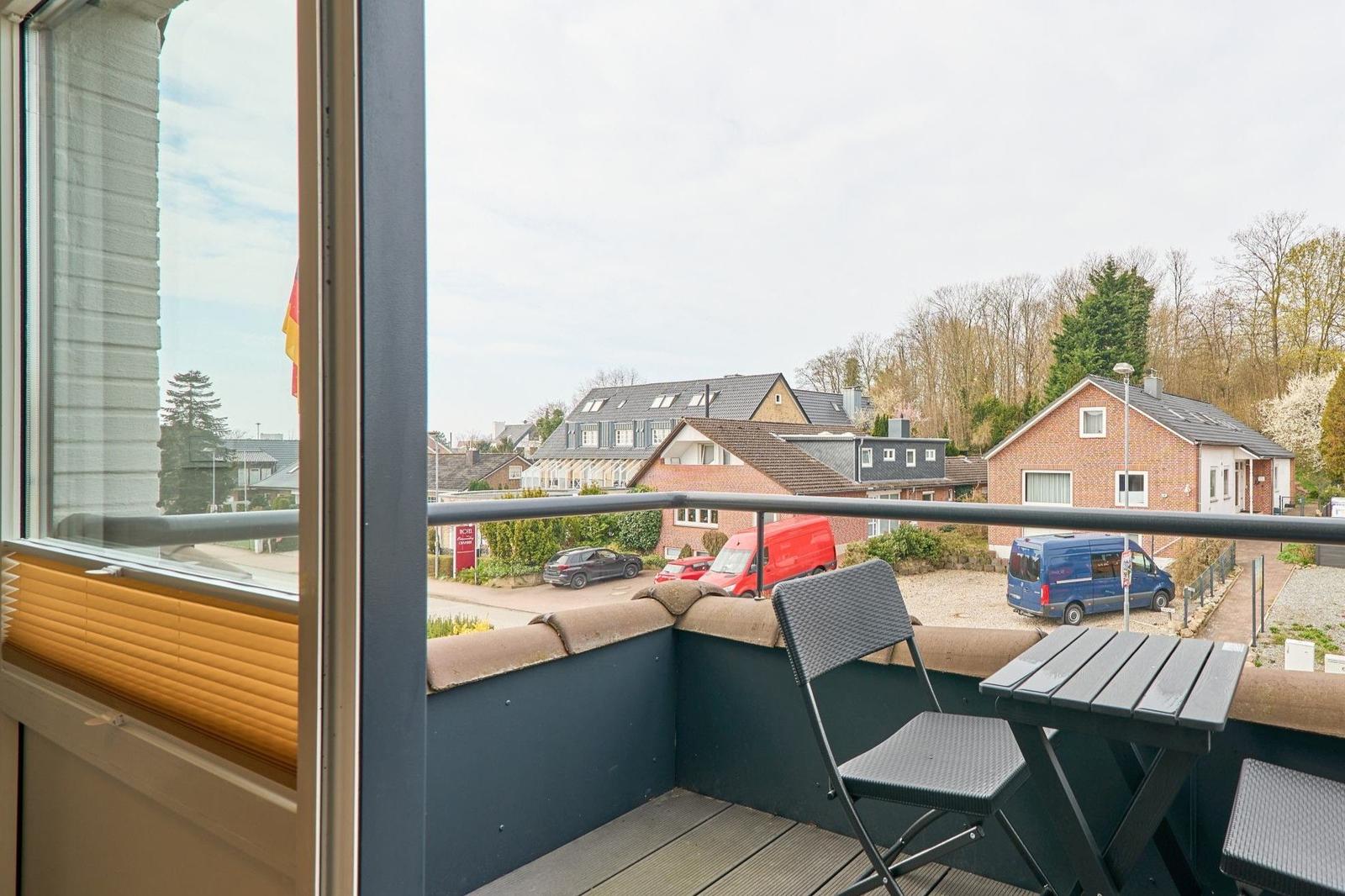 Balkon mit Tisch und Stühlen, Blick auf Straßen und Häuser im Stadtteil.