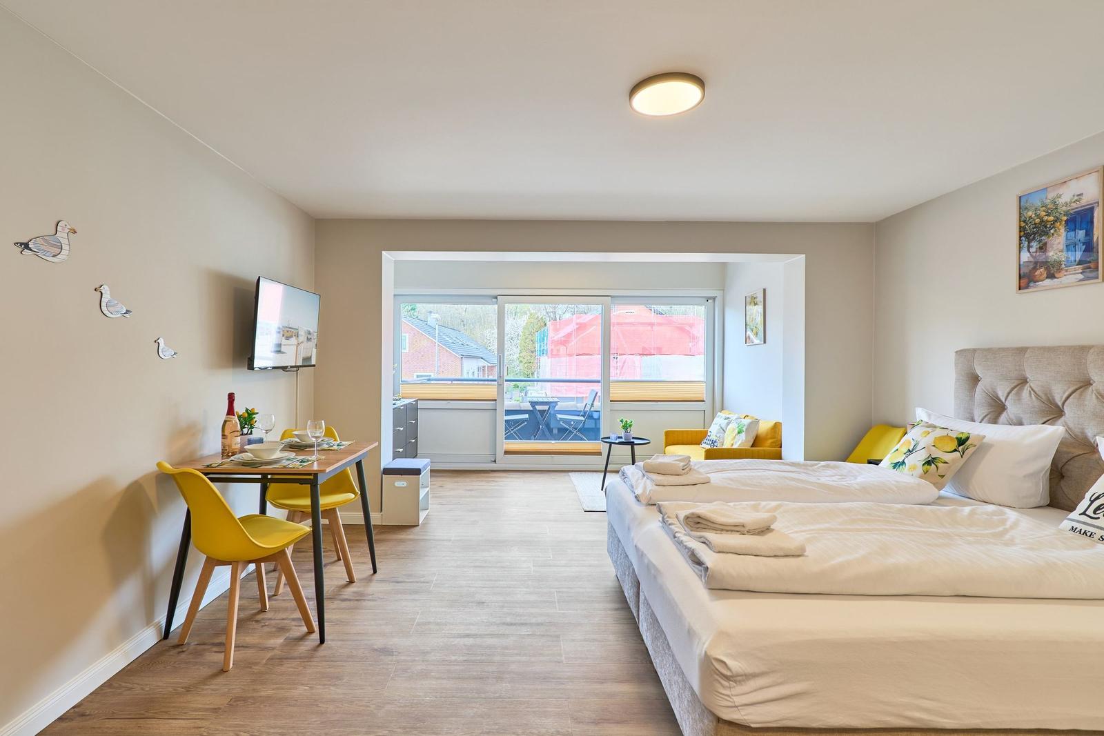 Ein Schlafzimmer mit Bett, Esstisch und Balkonansicht.