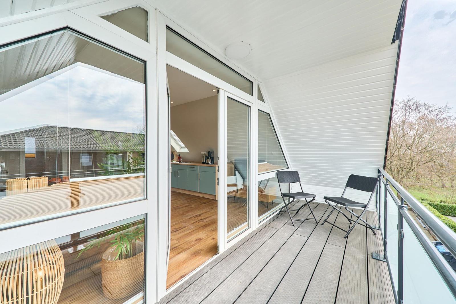 Terrasse mit zwei Stühlen und Blick auf Garten und Nachbarhaus.
